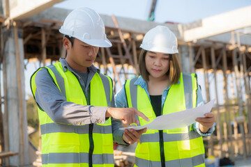 Structural engineer and foreman worker with blueprints discuss, plan inspecting for the outdoors building construction site.