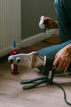 Male worker uses PPR Pipe welding machine near heating radiator