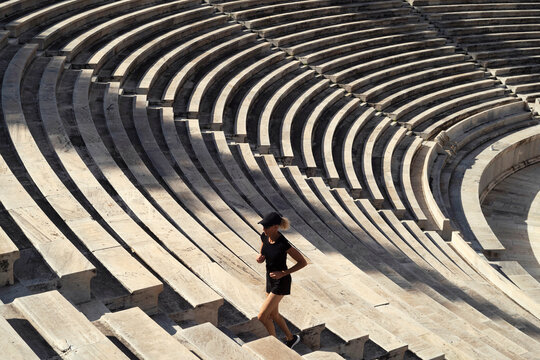 A woman runs in an ancient stadium.