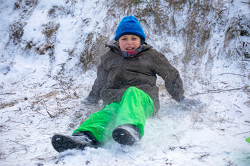 Fototapeta na wymiar happy boy goes down and plays on a snowy mountain in the Alps,