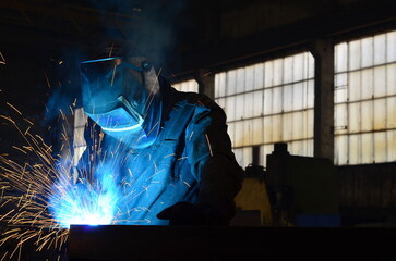 Workers wearing industrial uniforms and Welded Iron Mask at Steel welding plants, industrial safety first	