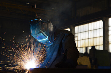 Workers wearing industrial uniforms and Welded Iron Mask at Steel welding plants, industrial safety first	