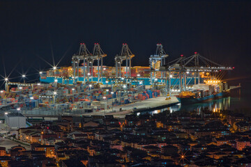 night drone view of container port and city houses