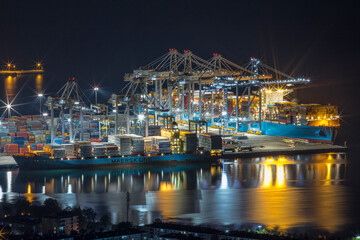Night drone view of the container port with giant cranes