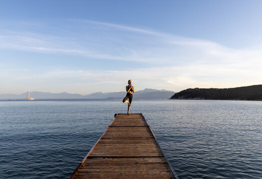 Woman in tree pose on jetty