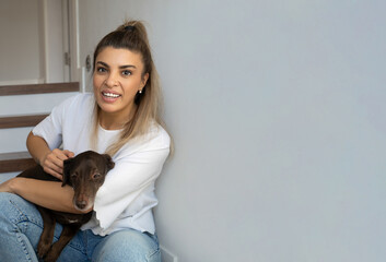 Brazilian Woman Embrace Her Favorite Pet Dog Dachshund Breed Sitting On Stairs At Home. Concept Of Friendship With Pet, Care, Veterinarian Health Wellbeing Animal. Copy Space