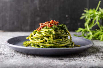Gragnano spaghetti with homemade rocket pesto and dried tomatoes. Dish suitable for adults and children, healthy and tasty. - obrazy, fototapety, plakaty