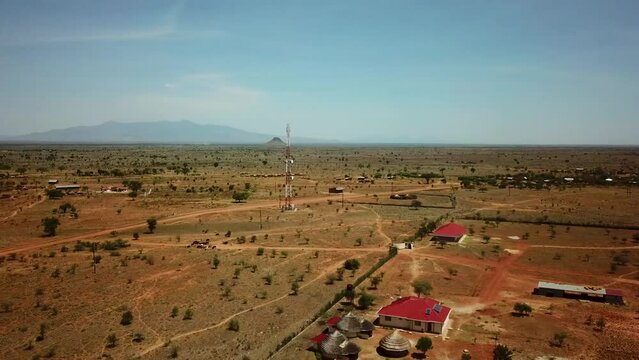 Panoramic aerial drone view of an area in Uganda with houses and a telecommunication antenna on a sunny day. High quality 4k footage