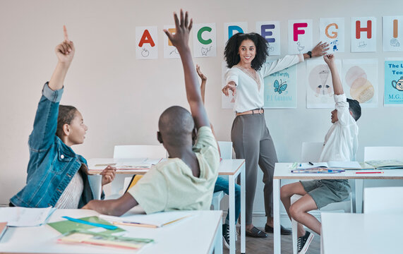 Question, Learning And Education At School With Kids Hands Raised To Answer Alphabet Assessment. Classroom, Learners And Tutor Teaching A Summary Information In A Class With Smart And Clever Group