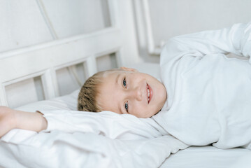 Obraz na płótnie Canvas Мальчик спит в кровати . белая постель