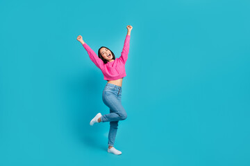 Full body portrait of ecstatic positive indonesian lady raise fists success empty space isolated on blue color background