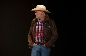 Portrait of adult man in cowboy hat against black background