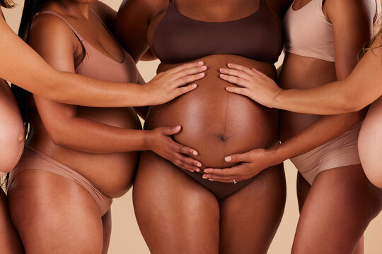 Women, hands or touching pregnancy stomach of black woman on studio background in growth support, love or community. Zoom, body or friends in pregnant underwear and belly feeling for baby health kick