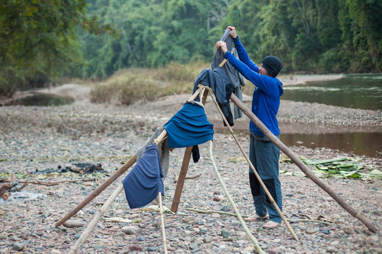 Man hanging clothes to dry while camping on the Nam Ou River in Phou Den Din National Protected Area, Phongsaly, Laos