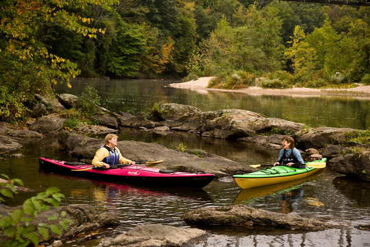 2 middle-aged women sea-kayak on Farmington River near Collinsville, Connecticut, USA.