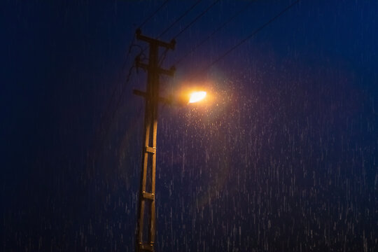 Rain drops under street lamp light in the dark of night.