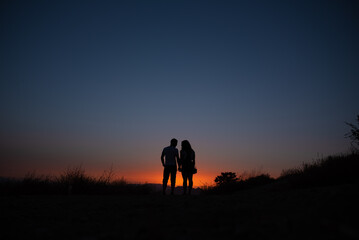 Silhouette of the couple against the sky at sunset.