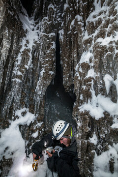 A young man takes a survey reading with compass and clinometer in an ice cave in Larsbreen, Svalbard.