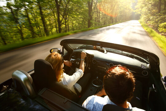 Blur-motion image of couple in convertible driving on the Blue Ridge Parkway