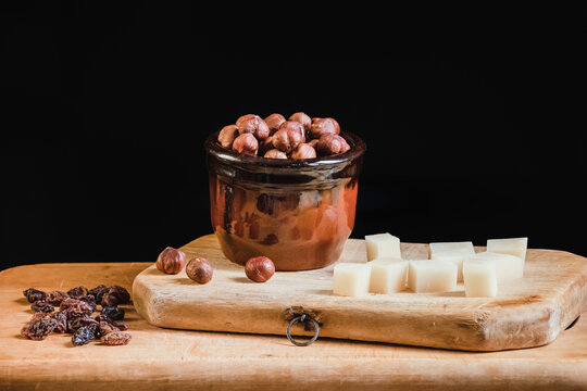 Still life of hazelnuts and cheese cubes on a kitchen wooden board