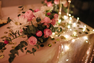Details candlelight date in a restaurant. Setting, date for two, Valentine's Day evening, burning candles. Bouquet of flowers and decor on table. Romantic dinner at home at night. Side view. Closeup.