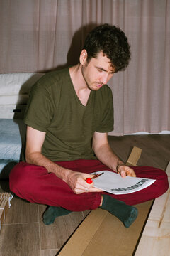 A curly-haired man studies the instructions for assembling a new bed