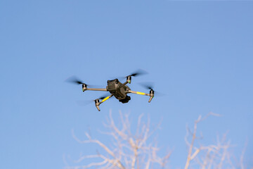 Flying drone with blue sky and clouds. copy space. A modern quadcopter with a high resolution camera soars in the air.
