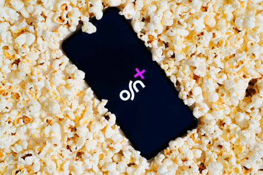 OSN pay TV channel on screen of smartphone, bunch of popcorn top view. Online movies and series, leisure and entertainment concept. Astana, Kazakhstan 25.01.2023