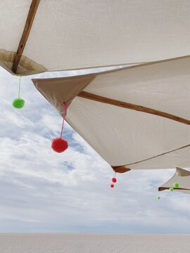 Pom poms hang from umbrellas on salt flat