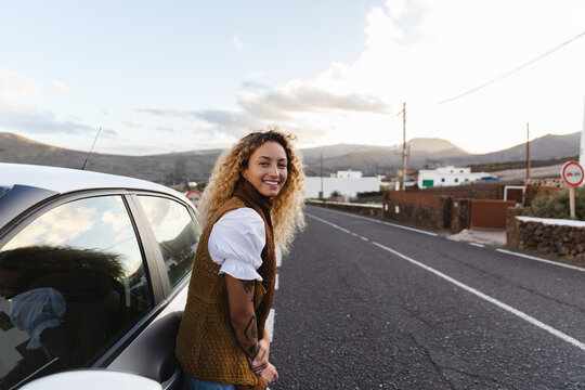 Woman leaning against car