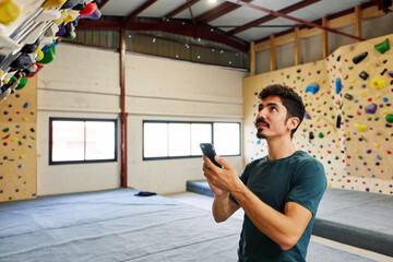 Sportsman using cellphone near climbing board