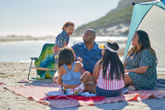 Happy family siting on blanket on sunny summer beach