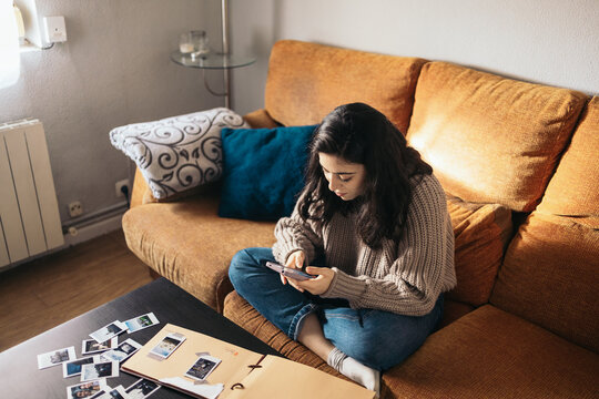 Woman Making A Scrapbook With Polaroid Photos And Using Smartphone