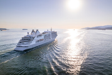 Fototapeta na wymiar Cruise ship sailing out of Vancouver harbour at sunset, cruise line, large boat, luxury cruise, aerial footage.