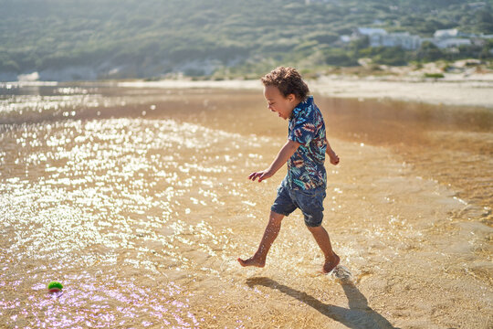 Carefree boy with Down Syndrome running and splashing in ocean surf