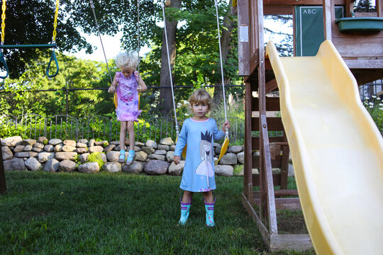 little girls playing on swingset in nightgowns rainboots early moring