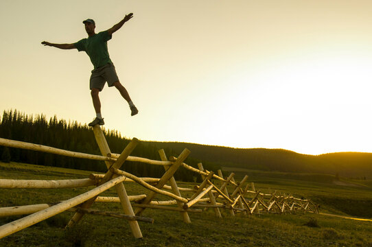 A man balancing on a fence at sunset, Rio Grande National Forest, Creede, Colorado(silhouette).
