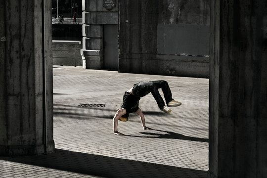 Young adult breakdancing under a bridge in Bilbao, Spain.