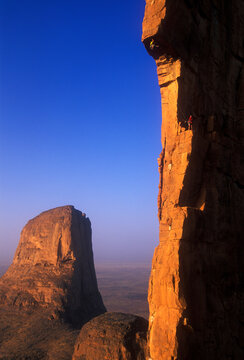 Two men climb one of the sandstone towers that is part of the Hand of Fatima in the Sahara Desert, Mali, West Africa.