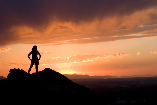 Woman in silhouette on mountain overlooking a city