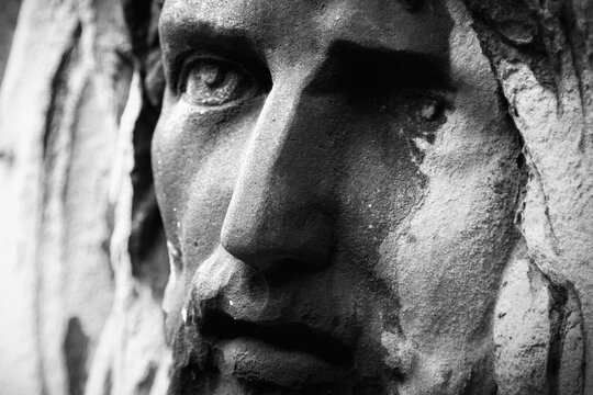 Fragment of an antique stone statue Jesus Christ in a crown of thorns. Close up. Black and white image.