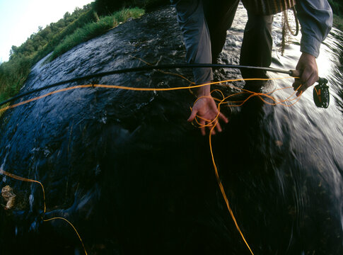 Fly fisherman gathering line from the stream's current.