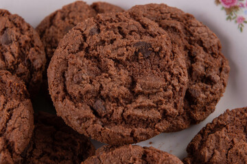 Tasty chocolate chip cookies on white plate on wooden background. Selective focus.