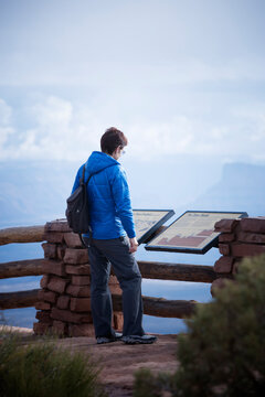 Rear view of a female hiker reading a interpretive sign at the Grand View Point Overlook, Canyonlands National Park, Utah.