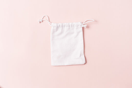 White pouch with a drawstring on a pink background.