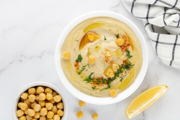 Classic hummus with parsley, olive oil, lemon in a plate on a white background. Top view. Arabic, Turkish cuisine.