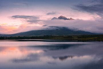Obraz premium Spectacular reflection of the mountains on a lake with mist under the midnight sun, fairy tale atmosphere in the Vesteralen Islands, Norway