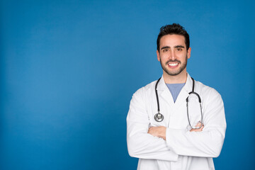 Caucasian young doctor smiling at the camera with arms crossed