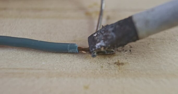 Tinned copper wire with tin. Soldering iron tip, melts tin, close-up, macro.