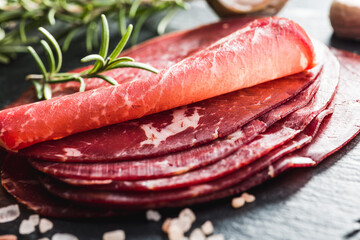 Smoked bresaola. Italian appetizer. Dried beef meat on black table.